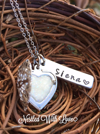 brown nest material holding silver necklace holding breastmilk with "Siena" charm