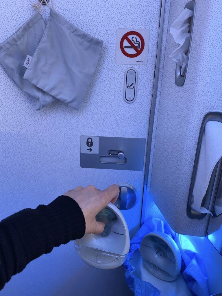 hand holding up elvie pump in an airplane lavatory